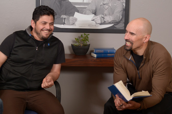 Two men sitting in chairs and smiling inside Harmony Recovery, our addiction treatment near Denver