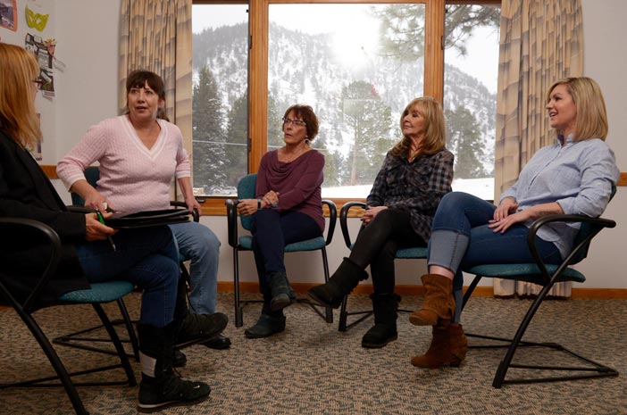Four women sitting together in chairs inside of Harmony Recovery, our rehab in Estes Park, Colorado