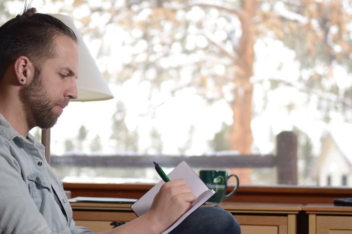 Harmony Recovery patron sitting by a window and writing in a book in our men's addiction recovery Colorado