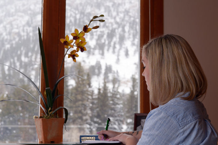 Woman sitting at a desk and writing inside Harmony Recovery, our women's addiction recovery Colorado